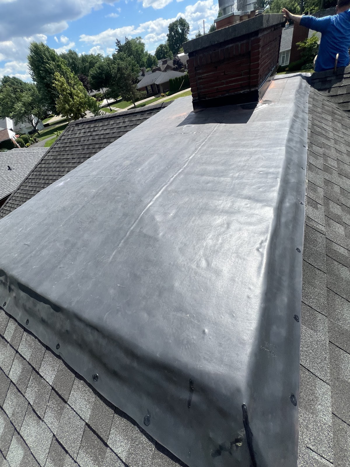 Finished residential EPDM roof beside shingle roofing in Grosse Pointe